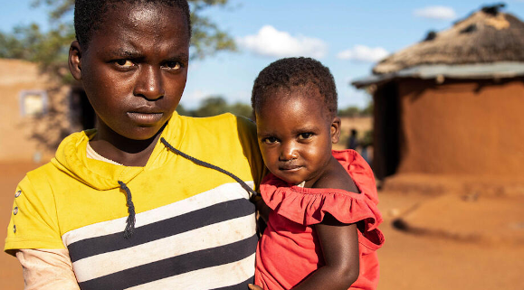 Thelma (1) is assessed during an Emergency Health Unit-supported nutrition survey in Zimbabwe (held by her sister Janet, 13). Image credit: Sacha Myers / Save the Children