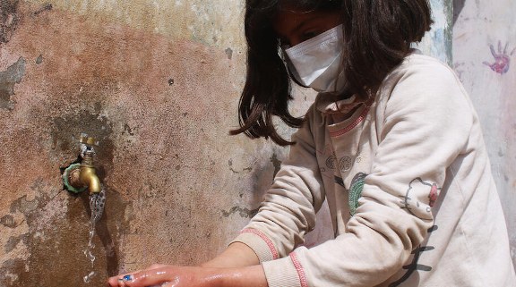 Tala*, 9 washing her hands. Image credit: GMU