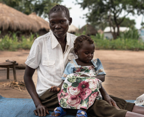 Celina* and her daughter Rose*, pose for a portrait close to Save the Children's mobile clinic in Mvepi refugee settlement. Image credit: GCCU