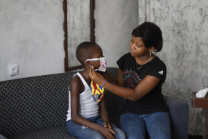 Eloge (15) helps her brother put his facemask on. Image credit: Christian Mutombo / Save the Children